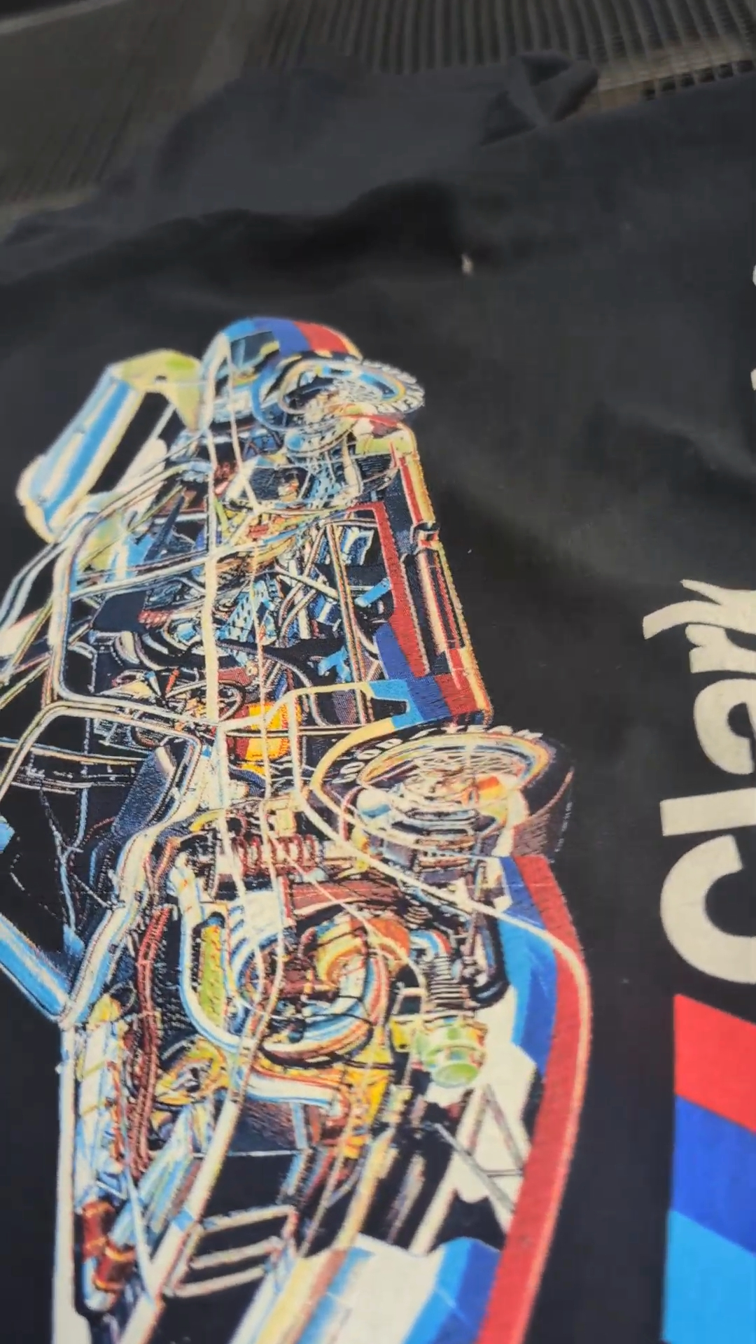 Close-up of the printed automotive illustration showing fine lines, multicolor detail, and the black shirt texture.